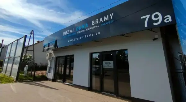 Nowoczesny salon okien i drzwi z szyldem "DRZWI OKNA BRAMY" i numerem 79a.